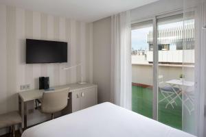 马德里NH马德里巴尔博亚酒店的配有一张床、一张书桌和一扇窗户的酒店客房