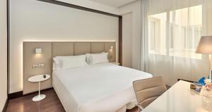 马德里NH马德里拉盖斯卡酒店的卧室配有一张白色的大床和一张桌子