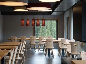 SchwandenBerghotel Mettmen的餐厅设有桌椅和大窗户。