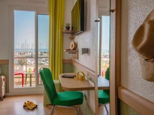 芒通芒通海岸宜必思快捷酒店的客房设有书桌、绿色椅子和阳台。
