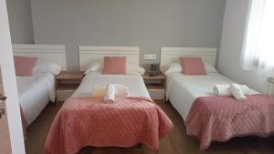 拉瓦克拉Pension Xacobeo Lavacolla的一间卧室配有两张带粉色和白色床单的床