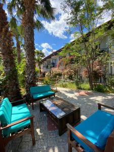 奥尔塔贾EON DALYAN BOUTIQIE HOTEL的一个带蓝色椅子和桌子的庭院,并种植了棕榈树