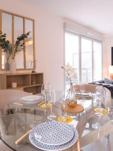 布雷斯地区布尔格Superbe appartement 2 chambres - parking gratuit的用餐室配有玻璃桌和酒杯
