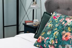 滨海韦斯顿Crookes House的一张带花卉枕头的床和一张桌子上的台灯
