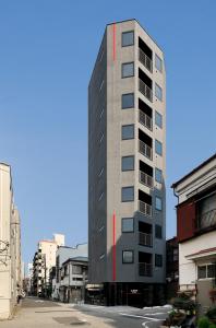 东京FL酒店 浅草東上野的一座高大的建筑,旁边是一条红色条纹
