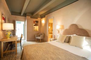 塞维利亚Hospes Las Casas Del Rey De Baeza, Seville, a Member of Design Hotels的一间卧室配有一张大床和一张带台灯的书桌