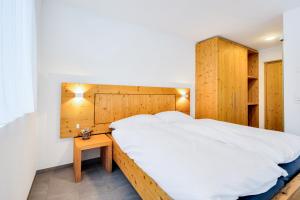布克斯Hotel Restaurant Berghaus Malbun Buchserberg的一间卧室设有一张大床和一个木制床头板