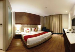 新德里Lemonwood Suites by F9 Hotels - Trivoli Garden Chhatarpur的酒店客房设有一张大床和一张书桌。