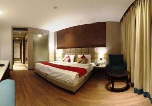 新德里Lemonwood Suites by F9 Hotels - Trivoli Garden Chhatarpur的酒店客房带一张大床和一把椅子