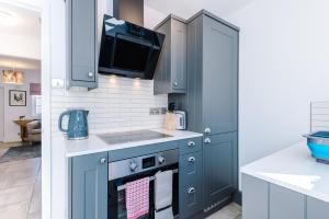 切斯特Stylish Home with Canal Views的厨房配有蓝色橱柜和炉灶上方的电视。
