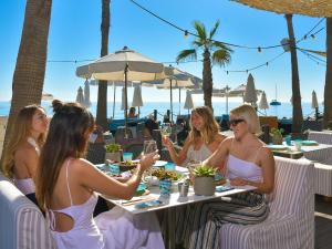 马贝拉Amàre Beach Hotel Marbella - Adults Only Recommended的一群坐在海滩上桌子上的女人