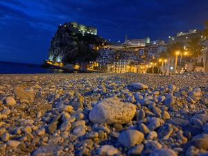 希拉IL Ritratto casa vacanza的夜间岩石海滩,有建筑和灯光
