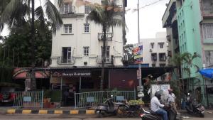 孟买Shine Hospitality Palace的两个男子骑摩托车在大楼前的街道上