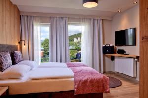 卡普伦HOTEL SONNBLICK Kaprun Salzburg - incl Zell am See-Kaprun Summercard的酒店客房设有一张床和一个大窗户