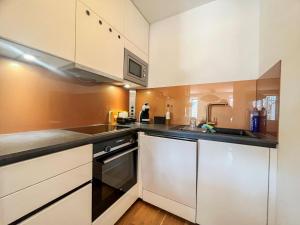 沃尔特湖畔佩莎赫Apartment Luxury Sunrise Appartement by Interhome的厨房配有白色橱柜和水槽