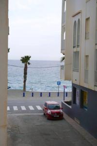 拉海瑞德拉Apartamento El Sol Naciente的停在海边的一条街道上的红色汽车