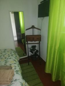 塞辛布拉Casa da Praia Alfarim的一间卧室配有一张床、一张桌子和一条绿帘