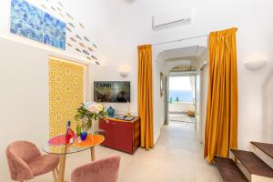 卡普里Suite Belvedere Capri Exclusive Rooms的客厅配有橙色窗帘和桌椅