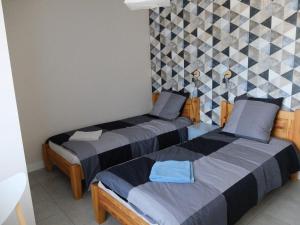 圣热尔韦莱班Thermalines的一间卧室设有两张床和瓷砖墙