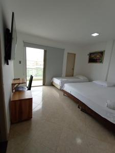 辛塞莱霍Hotel Palermo Sincelejo的一间卧室配有两张床、一张桌子和一台电视。