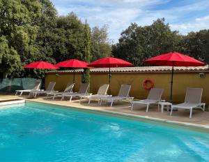 格里尼昂Logis La Bastide De Grignan Hotel & Restaurant "La Chênaie"的游泳池旁设有椅子和红色遮阳伞