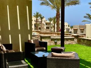 赫尔格达Apartment Azzura Sahl Hasheesh with private garden的庭院设有藤椅、桌子和草地