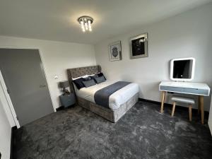 斯劳Two bed apartment with balcony Slough,Windsor,Legoland的一间卧室配有一张床、一张书桌和一台电视。