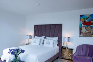 托马尔Hotel República Boutique Hotel的卧室配有一张白色大床和紫色椅子