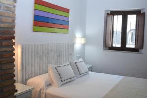 萨阿拉德洛斯阿图内斯多纳萝拉滨海旅舍的卧室配有白色床,墙上挂着色彩缤纷的绘画作品