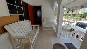 BelfastCharming 1-Bedroom House in St Thomas Jamaica的阳台的门廊配有2把白色椅子