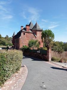 科隆热Château de Vassinhac chambres d'hôtes Collonges la rouge的街道上一座带屋顶的大型砖砌建筑