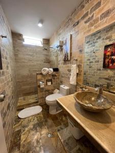 皮斯科Casa Villa Victoria en Pisco的一间带水槽、卫生间和石墙的浴室