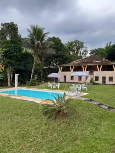 瓜皮米林Sítio dos Guedes的房屋前的带椅子和遮阳伞的游泳池