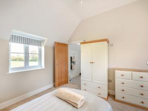CottamHorseshoe Cottage的白色的卧室设有床和窗户
