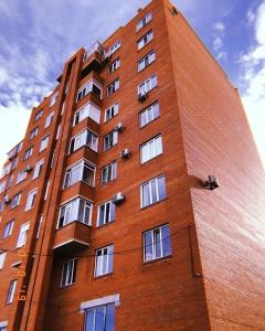 巴甫洛达尔Квартира в элитном ЖК的一座高大的红砖建筑,设有白色的窗户