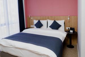 奇姆肯特Graf Hotel的一间卧室配有一张带蓝色枕头的大床