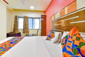 艾哈迈达巴德FabHotel Kadamb Inn的一间卧室配有一张带色彩缤纷枕头的大床