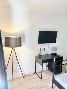 威斯巴登City Loft in Toplage Mainz-Kastel的客房设有一张带电视和台灯的书桌。