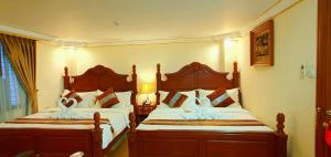 仰光联合广场酒店的一间卧室配有两张带白色床单的床