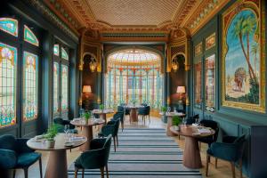 圣艾米隆格兰德巴拉伊城堡度假温泉酒店的用餐室配有桌椅和彩色玻璃窗