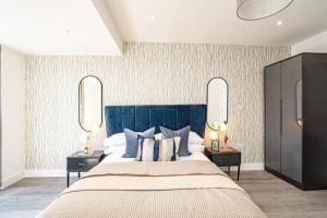赫默尔亨普斯特德Hemel Apartments- Elite Escape的一间卧室配有一张大床、枕头和镜子