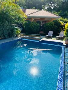 马埃岛贝拉扎尔区阿尔哈别墅的一个带长凳和房子的蓝色游泳池