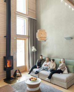 罗瓦涅米天际别墅酒店的家庭坐在客厅的沙发上,客厅设有壁炉