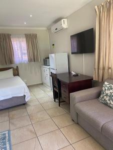 BoqateBotleng Guest House的酒店客房配有一张床、一张沙发和一张书桌。