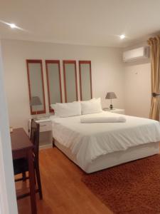 BoqateBotleng Guest House的卧室配有一张白色大床和一张书桌
