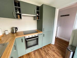 伯恩茅斯Hydeaway beautiful 3 bedroom house in a great location的厨房配有绿色橱柜和炉灶。