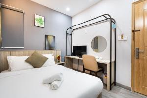 胡志明市The Cozy Inn Hotel Ho Chi Minh的一间卧室配有一张床、一张书桌和一面镜子