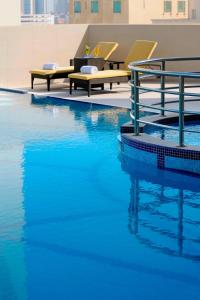 麦纳麦万豪麦纳麦居菲尔原住客栈酒店的大楼内一个带椅子和蓝色水的游泳池