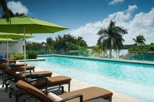 坎昆The Westin Cancun Resort Villas & Spa的一个带椅子和遮阳伞的游泳池