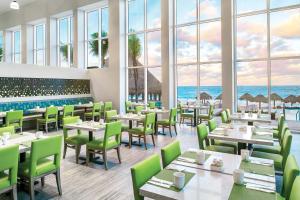 坎昆The Westin Cancun Resort Villas & Spa的餐厅设有桌椅,以大海为背景